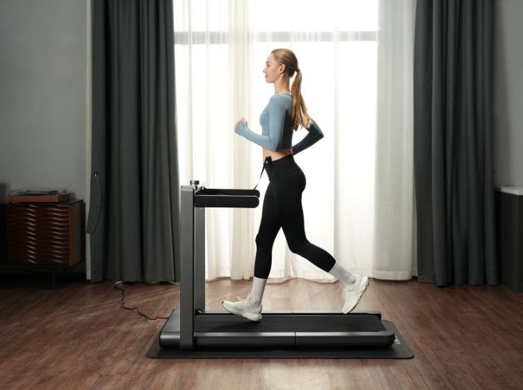 Person walking on a WalkingPad R3 Hybrid+ Foldable Treadmill in a bright living room.